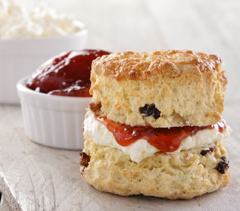 a cake stand with jam and cream scones and strawberries